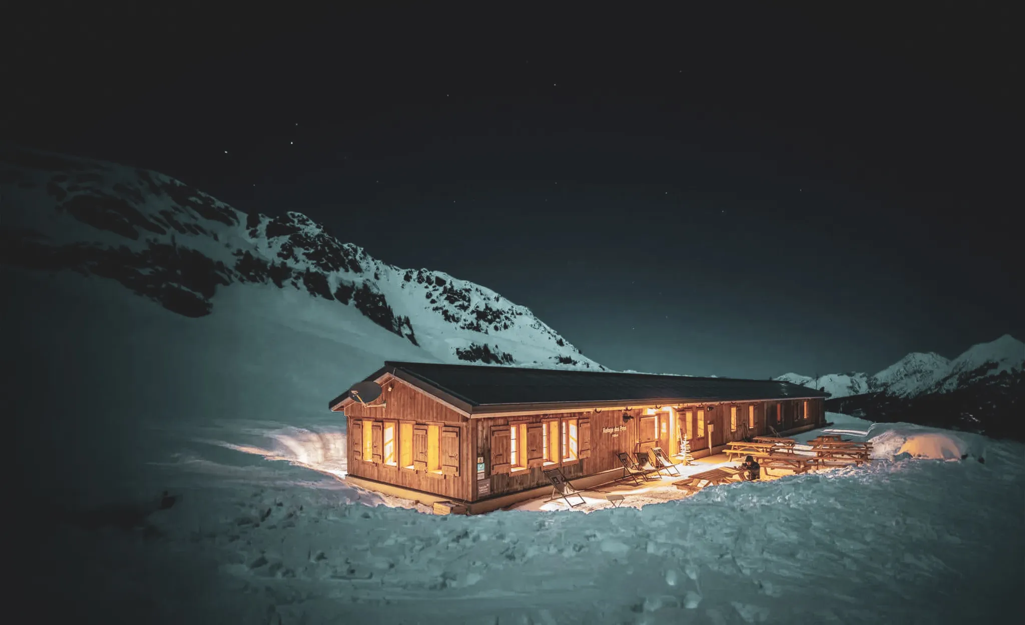 Een warm Berghut verlicht door de sterren in een betoverend sneeuwlandschap.