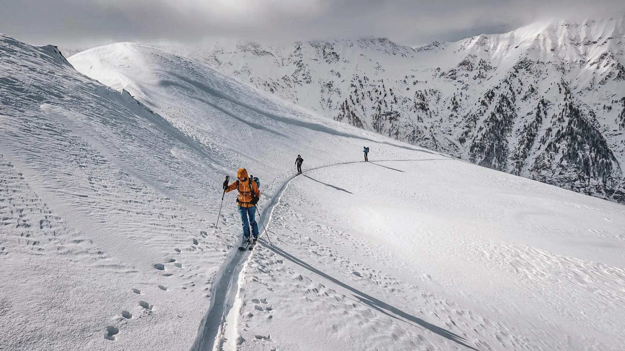 Three ski tourers on the snowy slopes of the Queyras