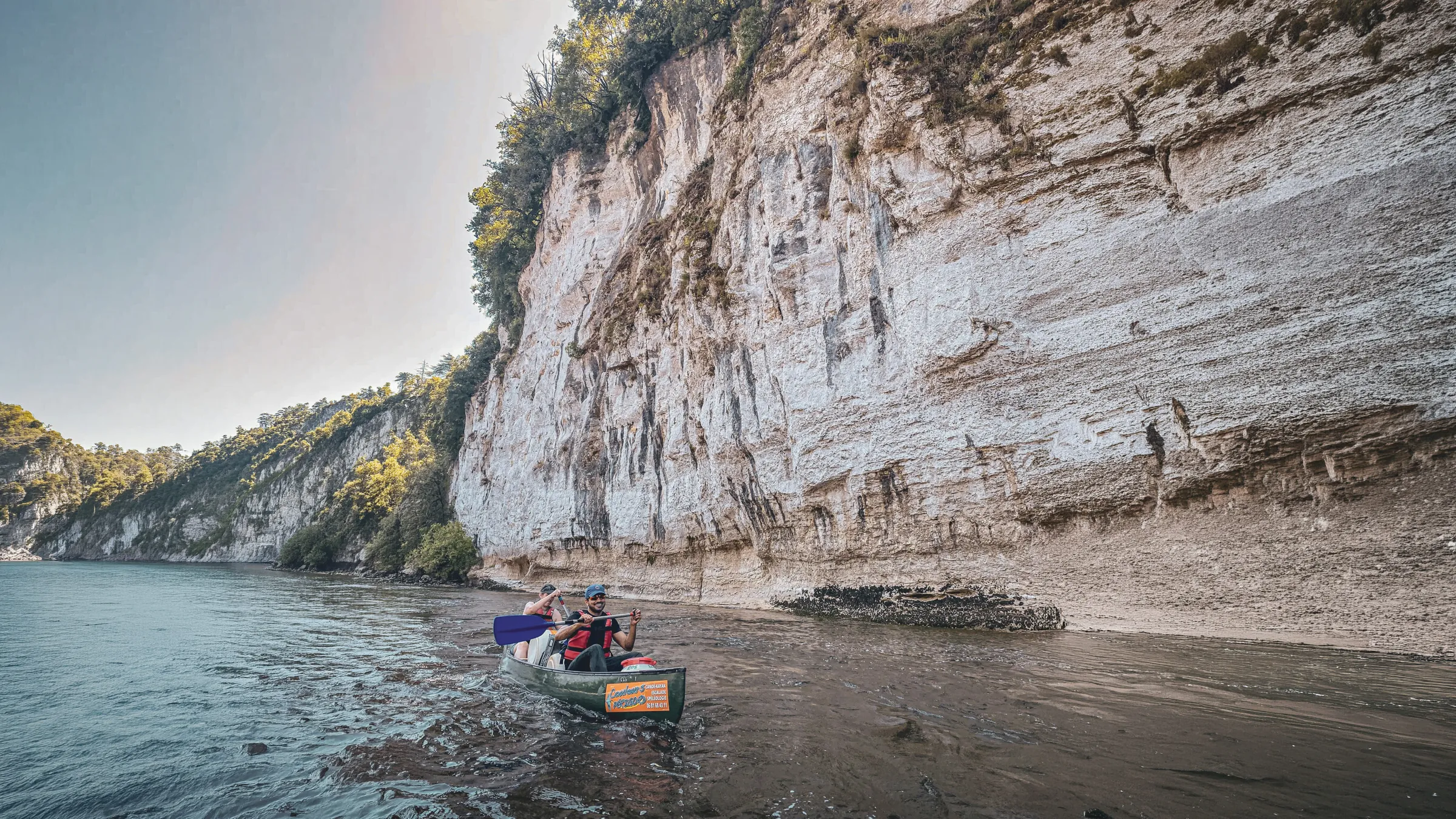 Canoë sur la Dordogne entouré de falaises calcaires majestueuses