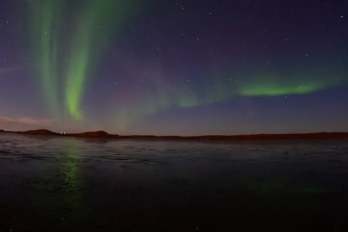 photo de nuit d'un ciel recouvert d'aurores boréales et des étoiles entre montagne et glace sur le Kungsleden 