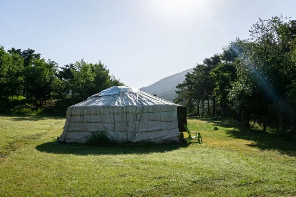 Découverte d'une yourte : yourte dans un paysage naturel avec des arbres et un beau ciel bleu avec du soleil