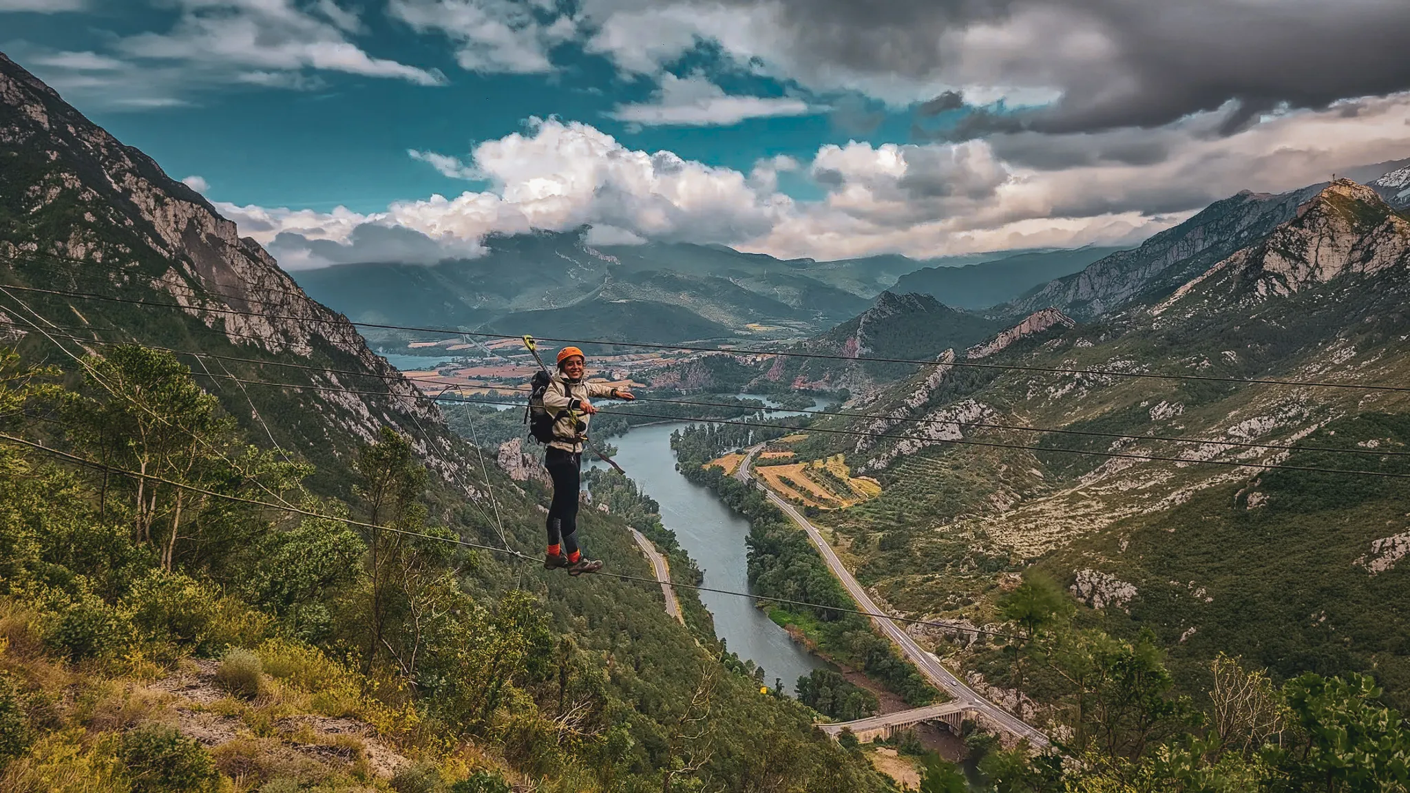 Een avonturier op een via ferrata voor beginners, voortdurend vastgeklikt, met uitzicht op berglandschappen.