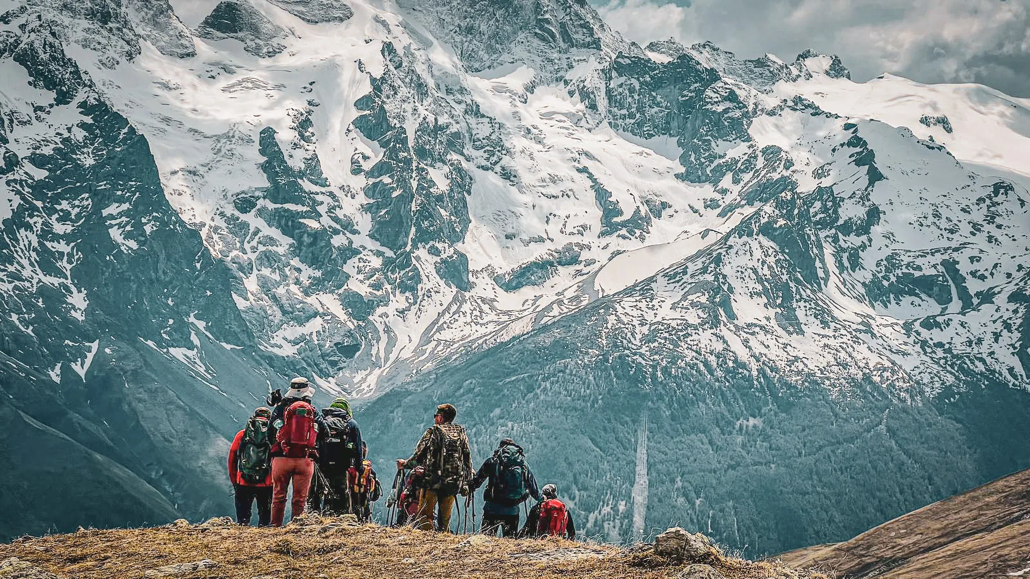 Een groep wandelaars bewondert majestueuze bergtoppen tijdens de trektocht rond de Aiguilles d'Arves met overnachtingen in berghutten.