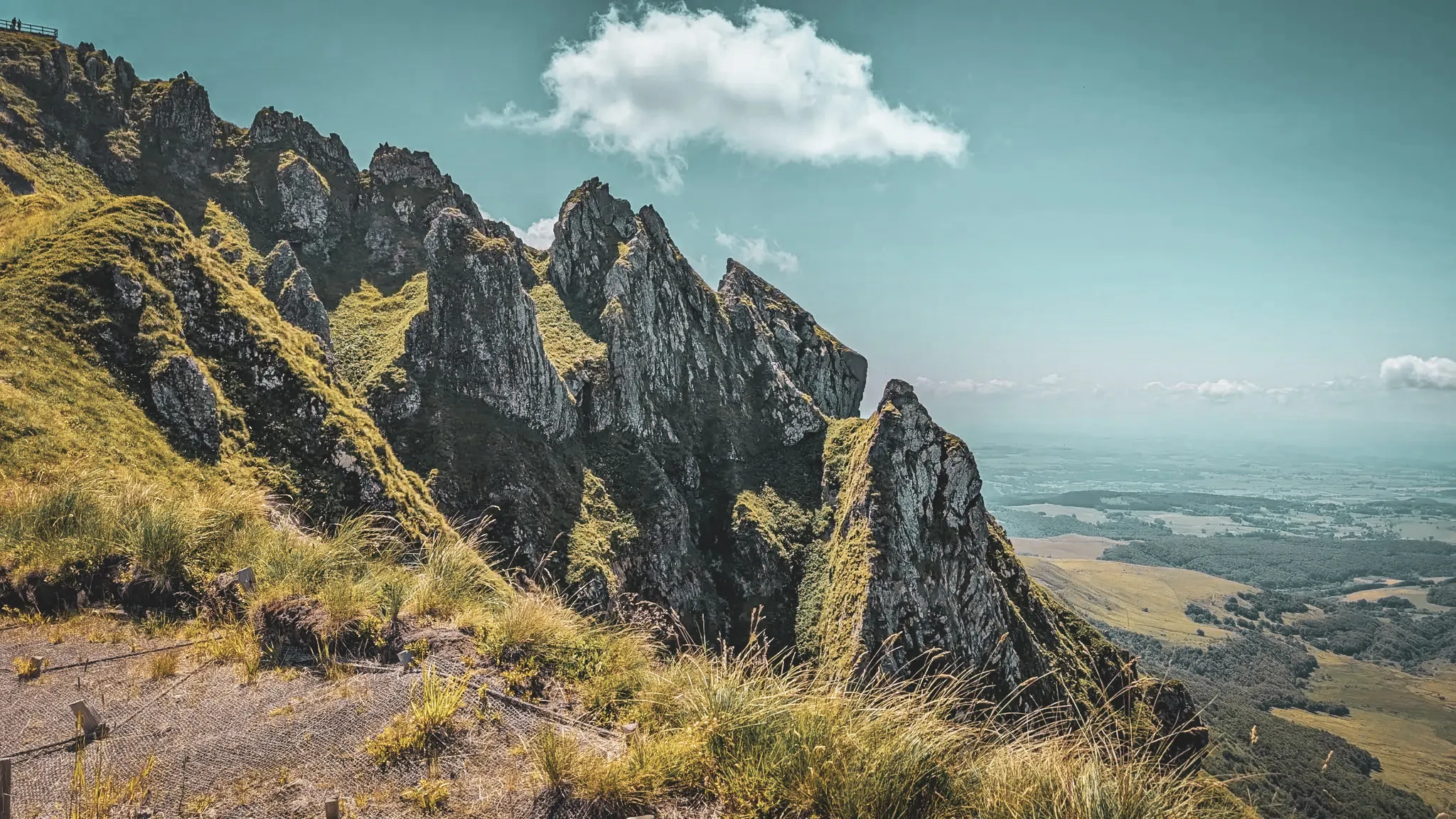 A breathtaking panorama of the Auvergne volcanoes, with steep ridges under a blue sky.