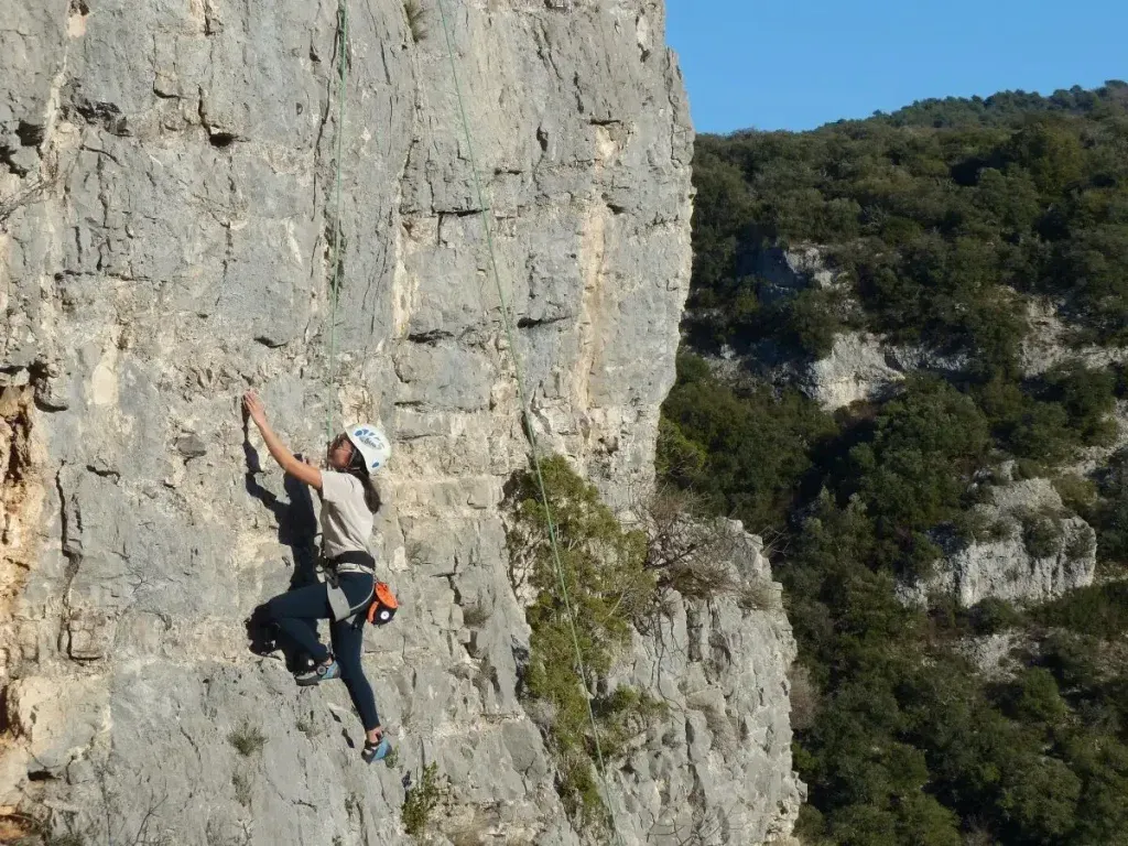 Femme en train de faire de l'escalade de voie sur une falaise 