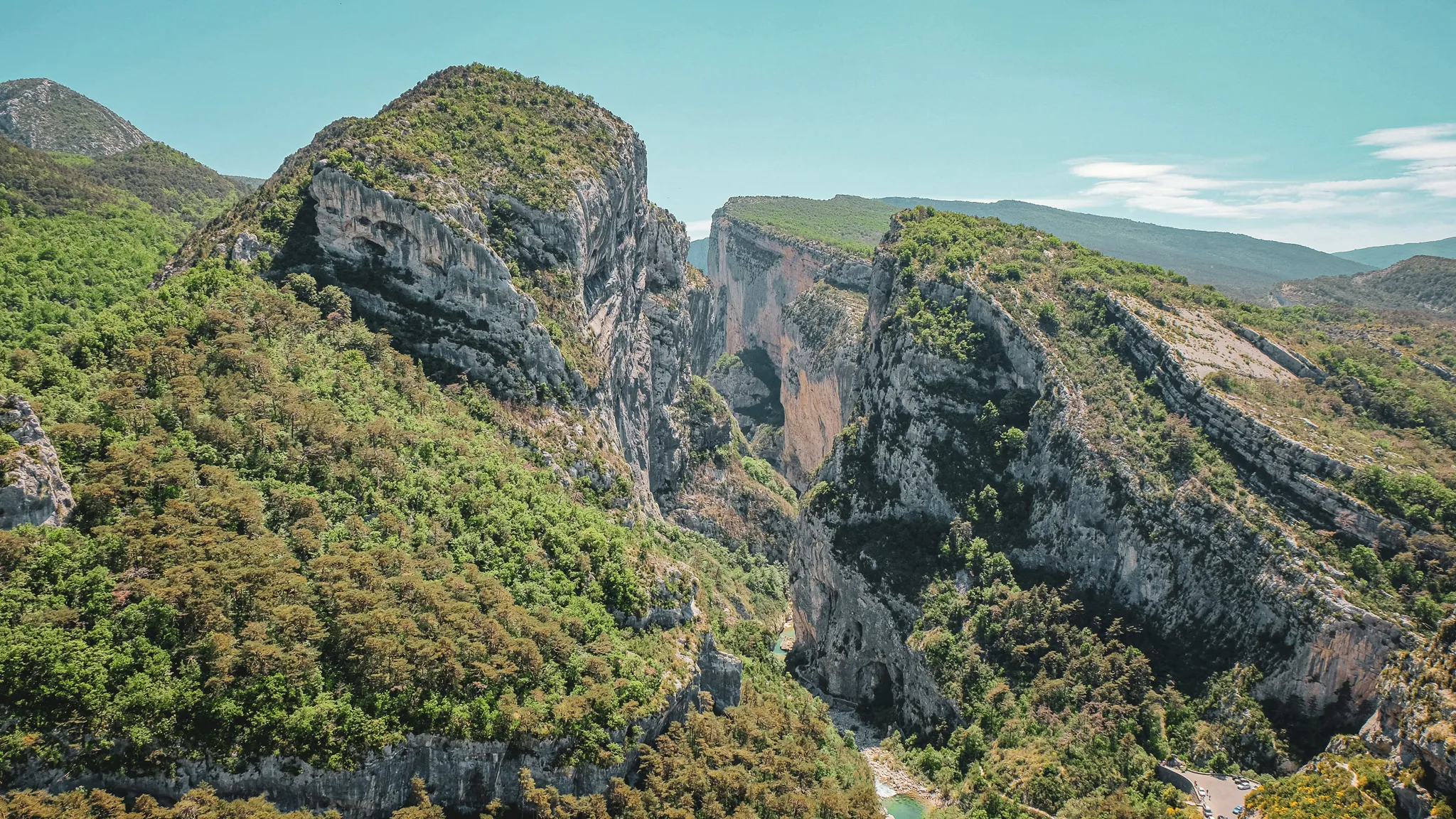 Panoramic view of the Gorges du Verdon, majestic cliffs plunging into lush green countryside.