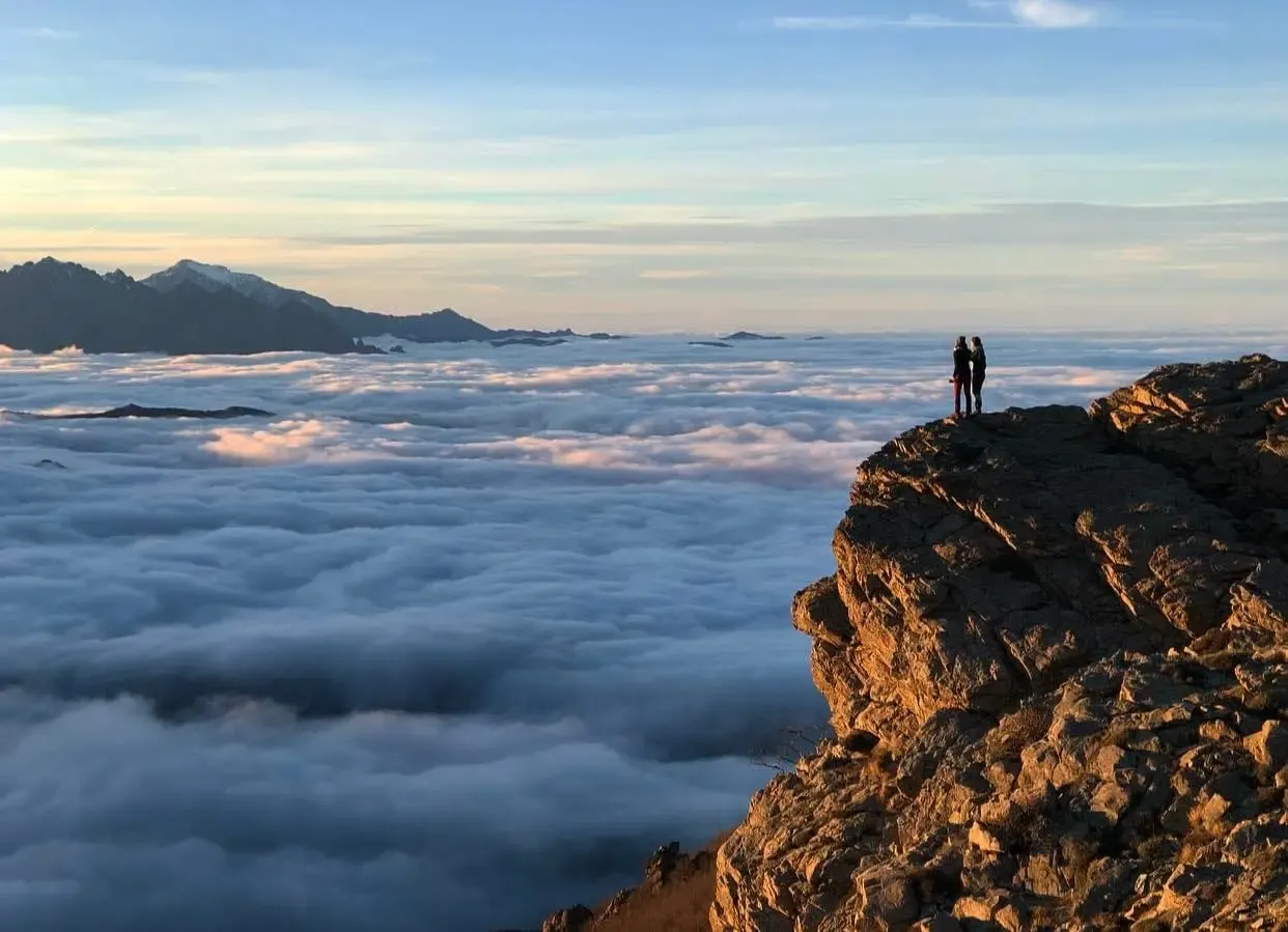 Deux courreuses au sommet d'une montagne en corse devant un tapis de nuage et des pics rocheux