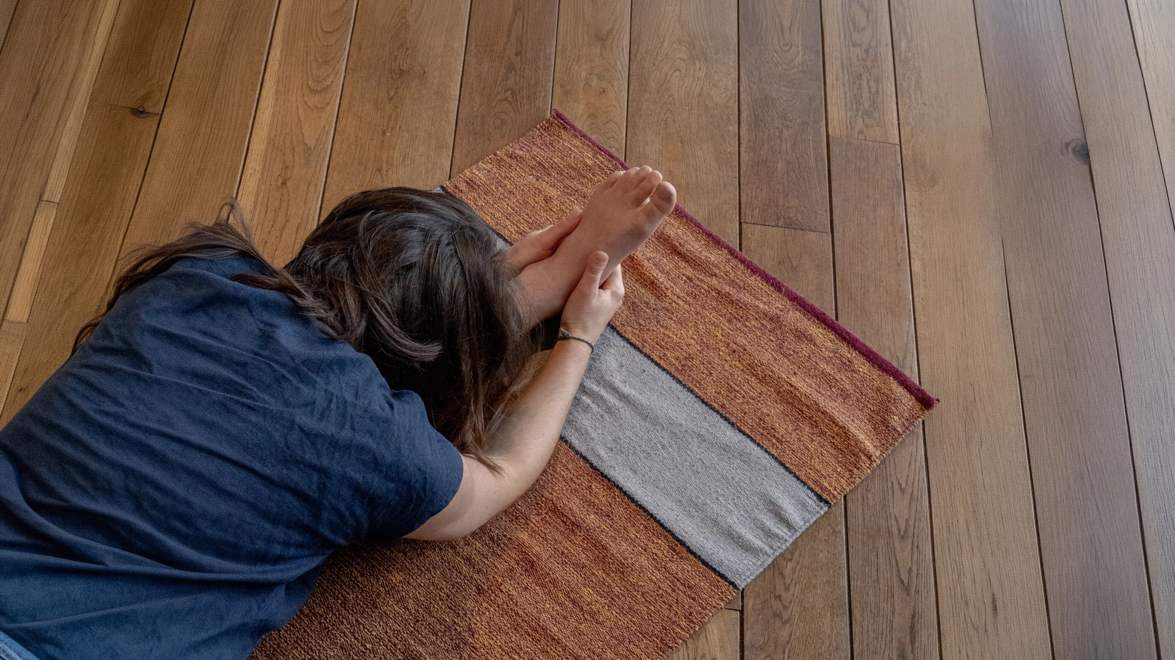 Woman meditating peacefully on a yoga mat, in a natural wood setting