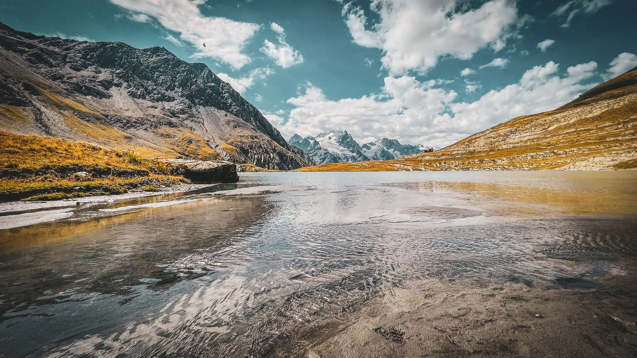 Een turquoise meer omringd door majestueuze bergen onder een zonnige hemel, een uitnodiging om te ontsnappen naar de Alpen.