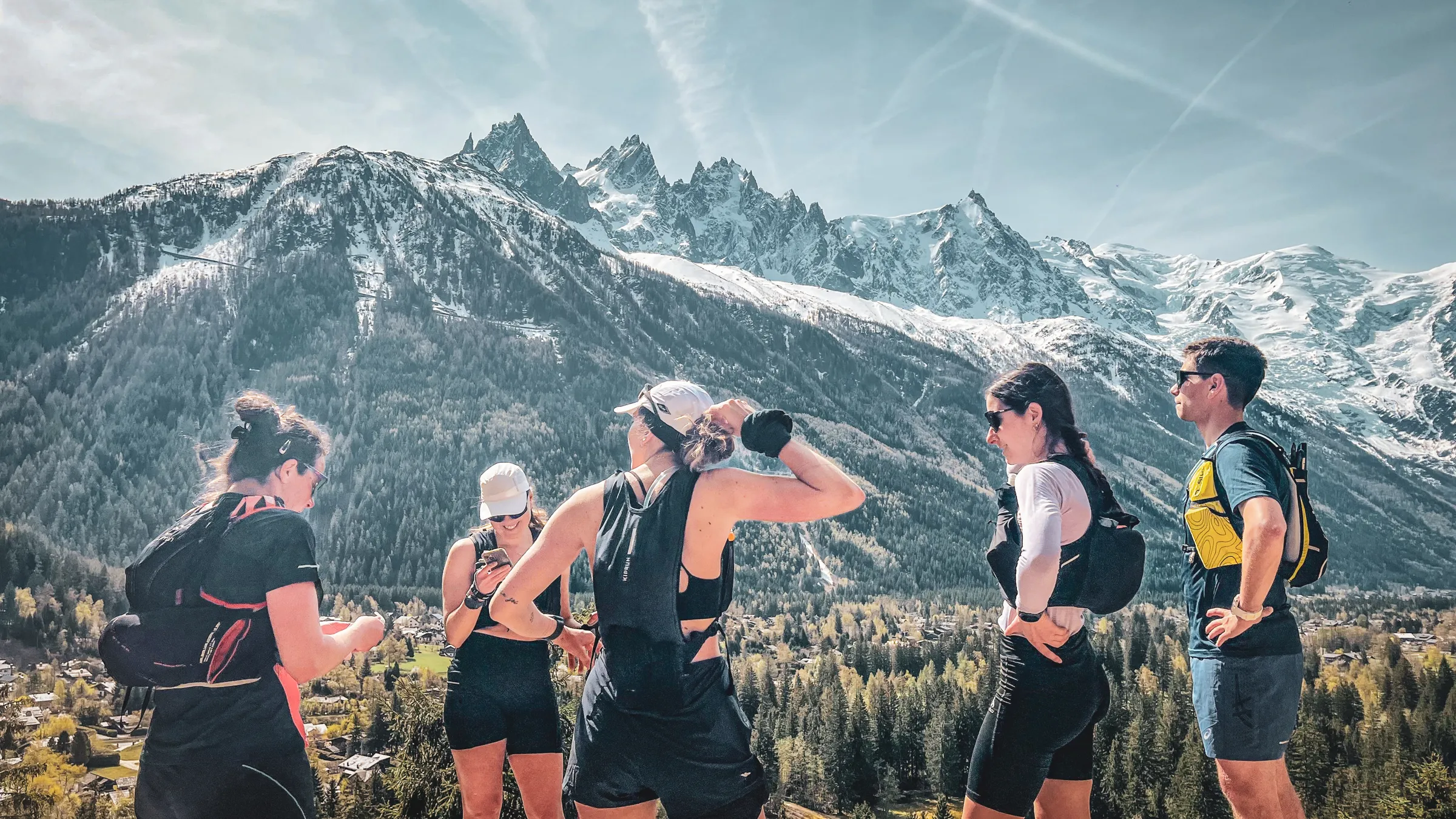 A group of runners in the mountains, with the snow-capped peaks of Mont Blanc in the background, in a dynamic atmosphere.