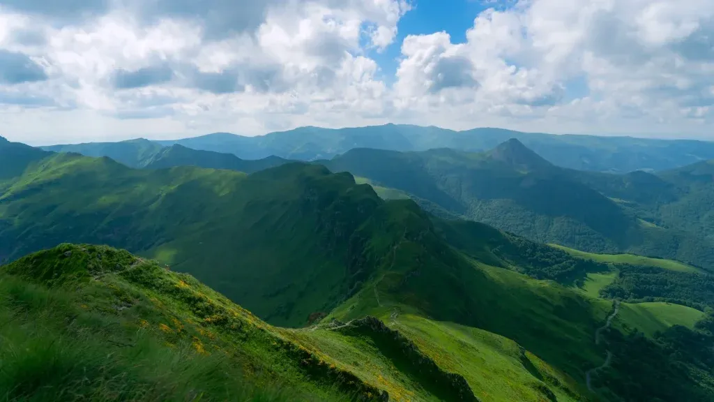 Paysage que l'on peut observer lorsque l'on fait une balade dans les Cévennes. Il y a une chaîne de montagnes et un ciel bleu avec quelques nuages.