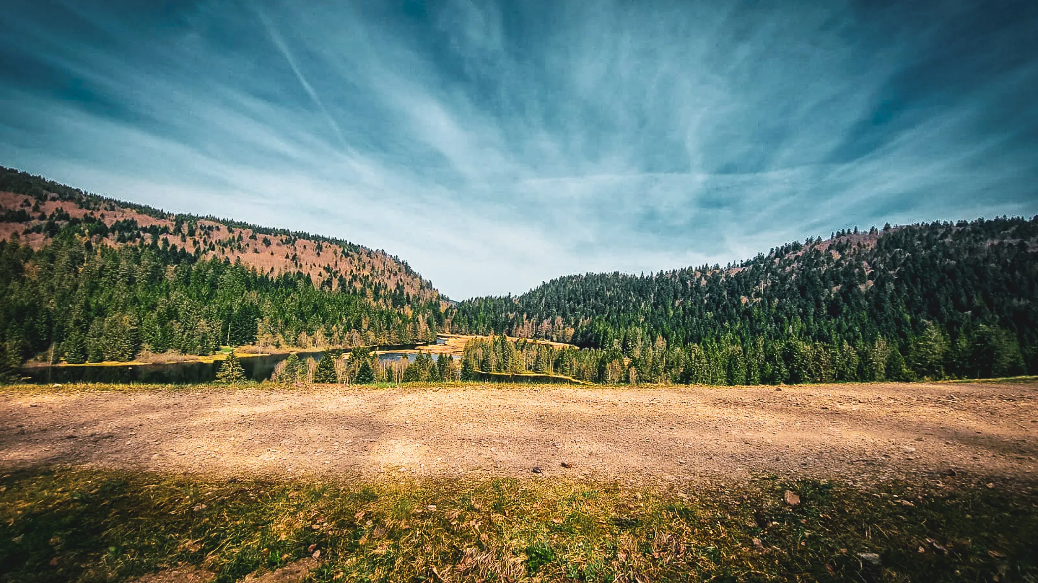 A Vosges landscape of lakes and lush green forests under a blue sky, inviting you to escape.