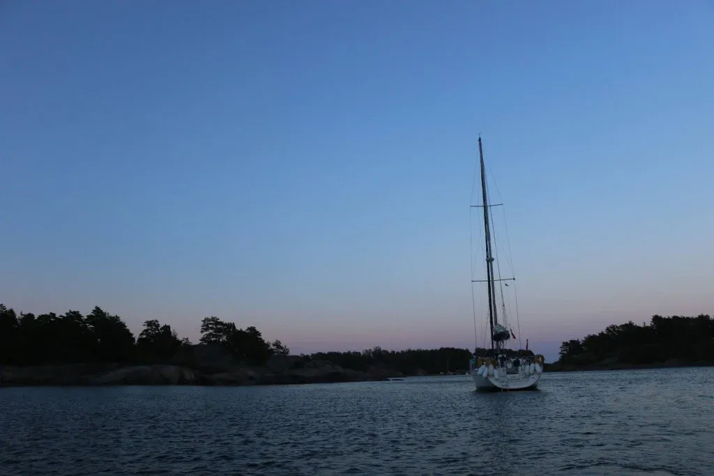 Voilier naviguant sur la mer baltique, devant un coucher de soleil au bord de la Suède