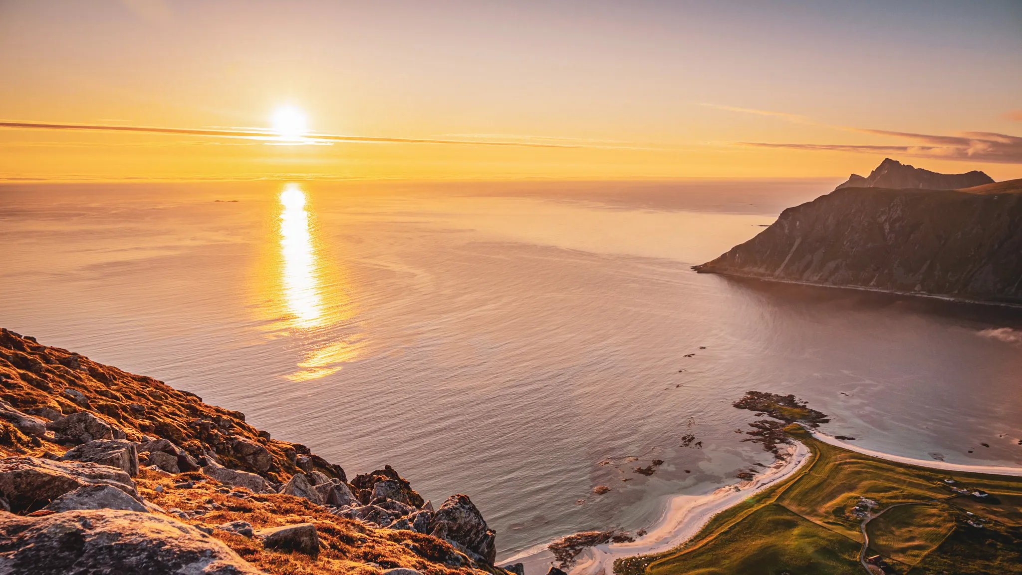 A dazzling sunset over the Lofoten Islands, between calm seas and majestic mountains.