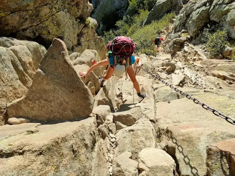 Personne descendant un passage délicat avec une chaîne sur le GR20 grande randonnée 20 en Corse